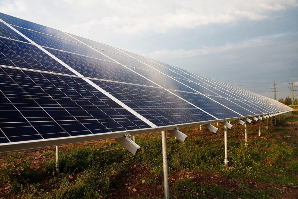A field of solar panels with rays of sunlight breaking through white clouds, showcasing the power and efficiency of a solar system for renewable energy.
